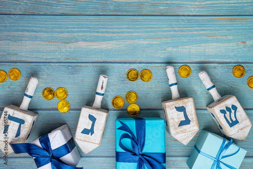 Dreidel, dreidle or dreidl with blue lettering on wooden background. Gift box, spinning top, Jewish holiday of Hanukkah, Jewish teetotum, gold coin photo