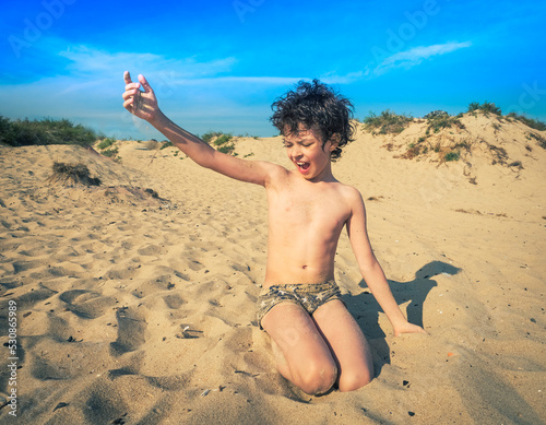 Cute little brunet boy on the beach plays with sand. kids travel concept. Sea holidays, copy space.