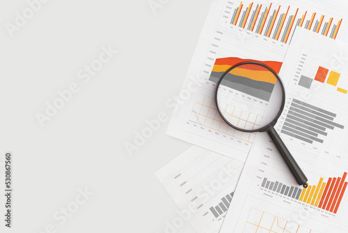 Business graphs, charts and magnifying glass on table. Financial development, Banking Account, Statistics