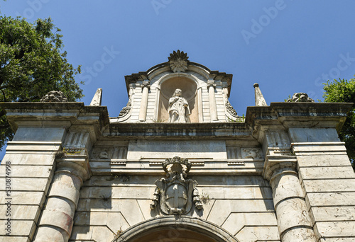 Low-angle view of the top of the Porta Romana (12th century), ancient city gate with the coat of arms of Genoa and a votive shrine of the Virgin Mary, Sarzana, La Spezia, Liguria, Italy