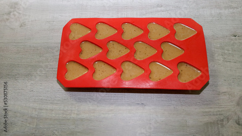Almond butter, coconut oil and cinnamon mixture in heart shape silicone mold for making fat bombs. photo