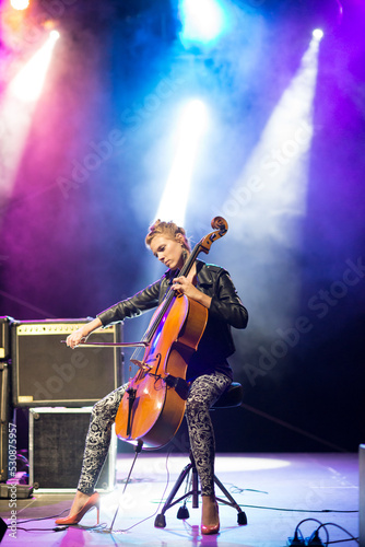 Young woman playing cello on the concert stage at night