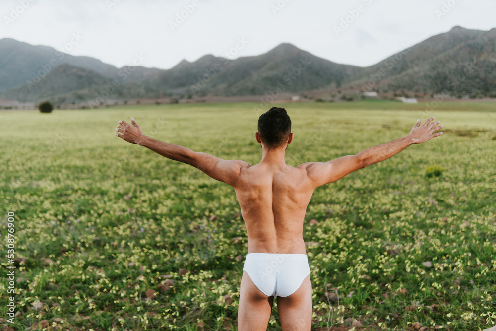 © ADDICTIVE STOCK - Anonymous shirtless guy admiring nature while standing in field with outstretched arms