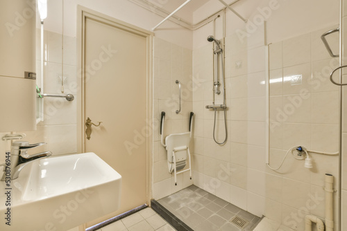 Interior of disable shower cabin with faucet and tiled walls