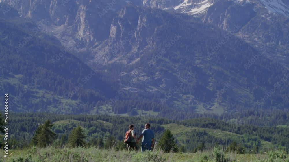 Adventurous backpackers wandering along rocky landscape. Man and woman exploring breathtaking backcountry of alpine terrain in Grand Teton National Park, WY, USA. High quality 4k footage Adventurous backpackers wandering along rocky landscape. Man and woman exploring breathtaking backcountry of alpine terrain in Grand Teton National Park, WY, USA. High quality 4k footage
