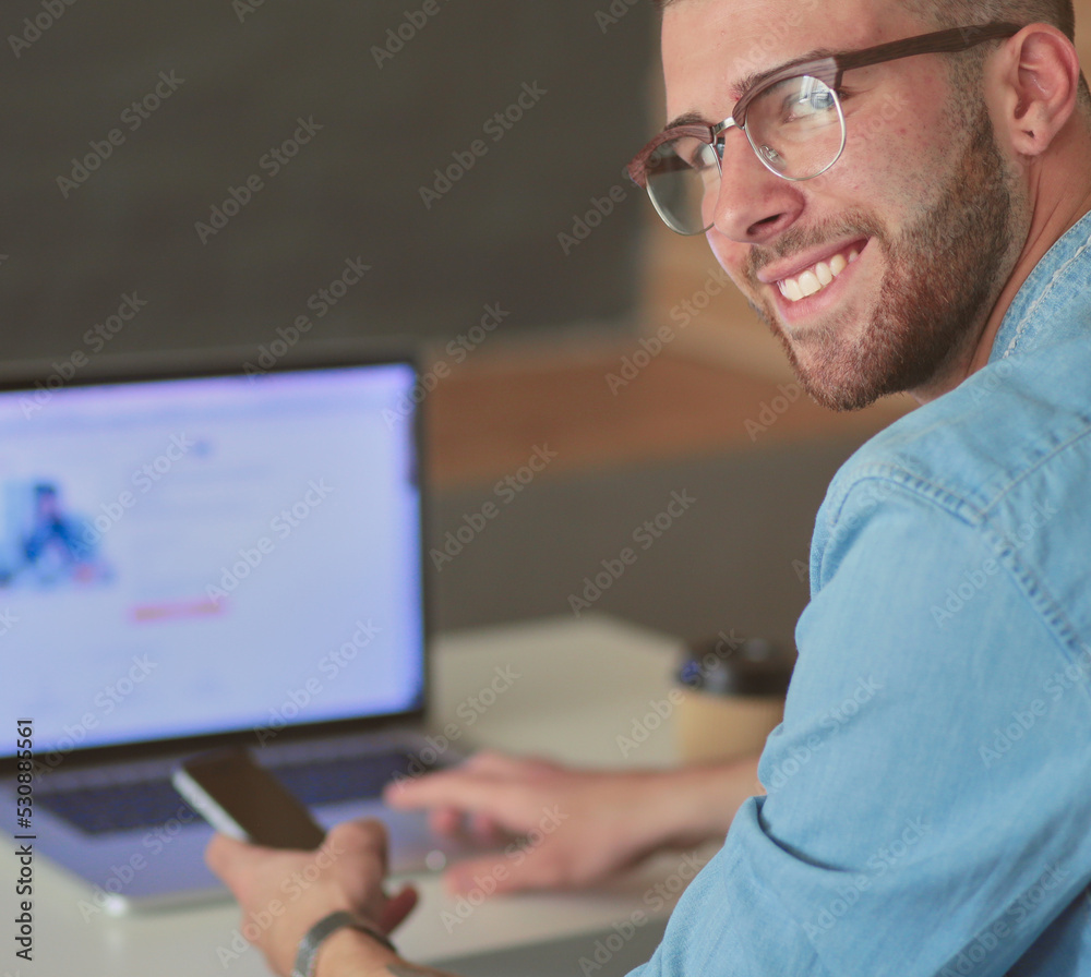 Young man using phone and works on the laptop. Young man using phone and works on the laptop.