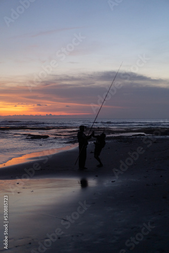 A fisherman is fishing with a fishing rod on the ocean, Bali, Indonesia.