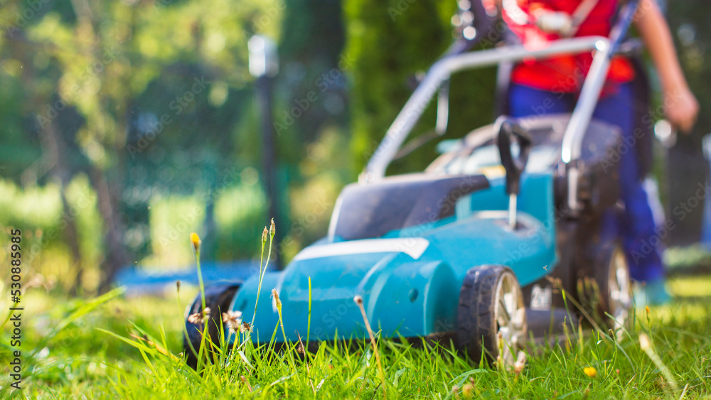 Lawn mover on green grass in modern garden or backyard. Machine for cutting lawns. Gardening care tools and equipment Lawn mover on green grass in modern garden or backyard. Machine for cutting lawns. Gardening care tools and equipment