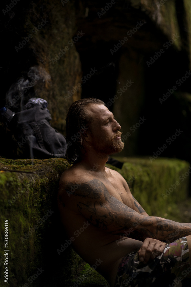 A man in a sacred temple with a waterfall in Bali, incense, Bali traditions, places of power.