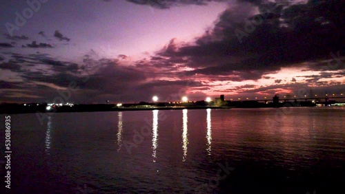 Night time lights reflecting on a river purple ominous skies with city lights in the background aerial video photo