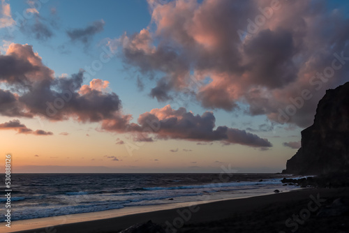 Scenic view during sunset on the volcanic sand beach Playa del Ingles in Valle Gran Rey, La Gomera, Canary Islands, Spain, Europe. Massive cliffs of the La Mercia range. Close up on Rock formation photo