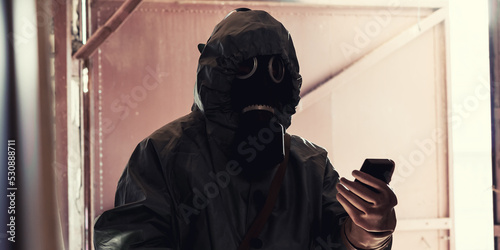 Man in protective coat with dosimeter in hand checking radiation level inside of ruined building photo