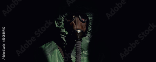 Portrait of person in gas mask and green protective costume isolated on black background closeup