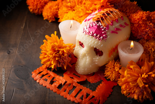 Sugar skulls with Candle, Cempasuchil flowers or Marigold and Papel Picado. Decoration traditionally used in altars for the celebration of the day of the dead in Mexico photo