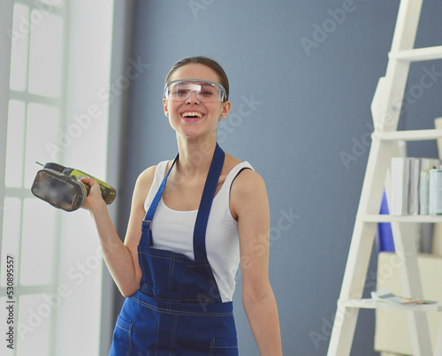 Worker woman with drill standing in new home.