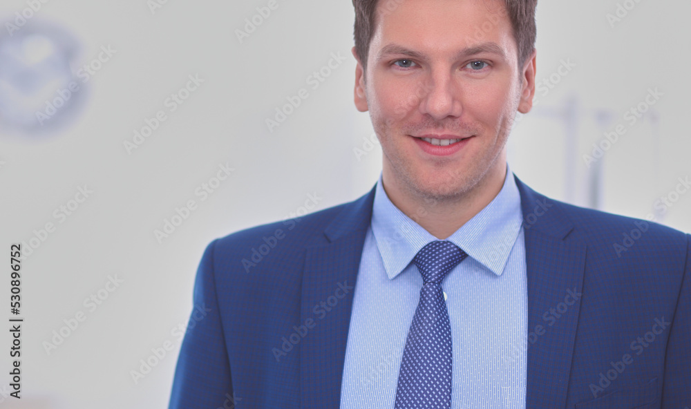 Business man or manager standing against his desk at the office Business man or manager standing against his desk at the office