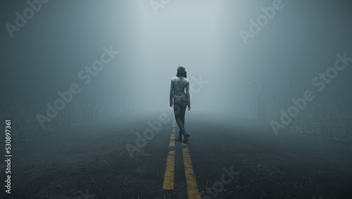 Woman walking alone down foggy road in forest