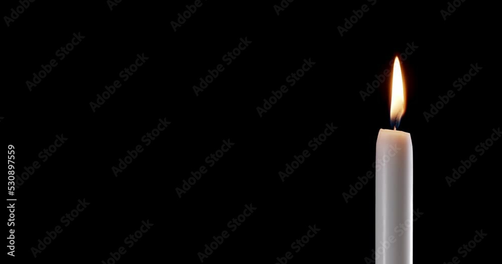 A single white candle burning.Isolated candle burning with dark background.White paraffin candle with yellow shades burns on a black background.Background or illustration of remembrance or celebration A single white candle burning.Isolated candle burning with dark background.White paraffin candle with yellow shades burns on a black background.Background or illustration of remembrance or celebration