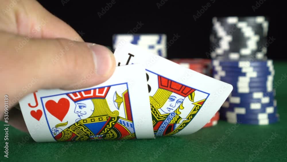 Poker game with a pair of jacks betting all the poker chips. Close-up of a gambler hand is holding playing cards in poker club