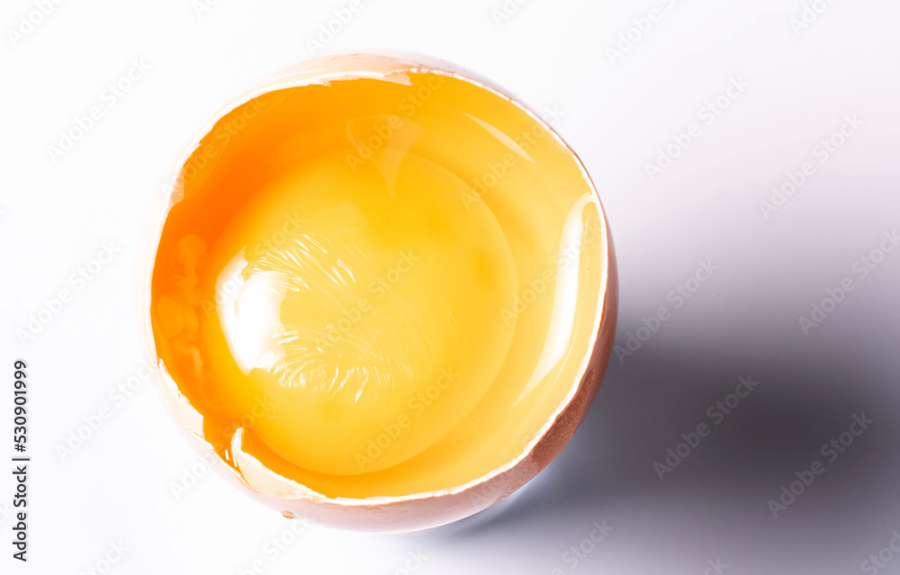 Egg yolk in a shell isolated on a white background. Egg yolk close-up. Broken chicken egg.