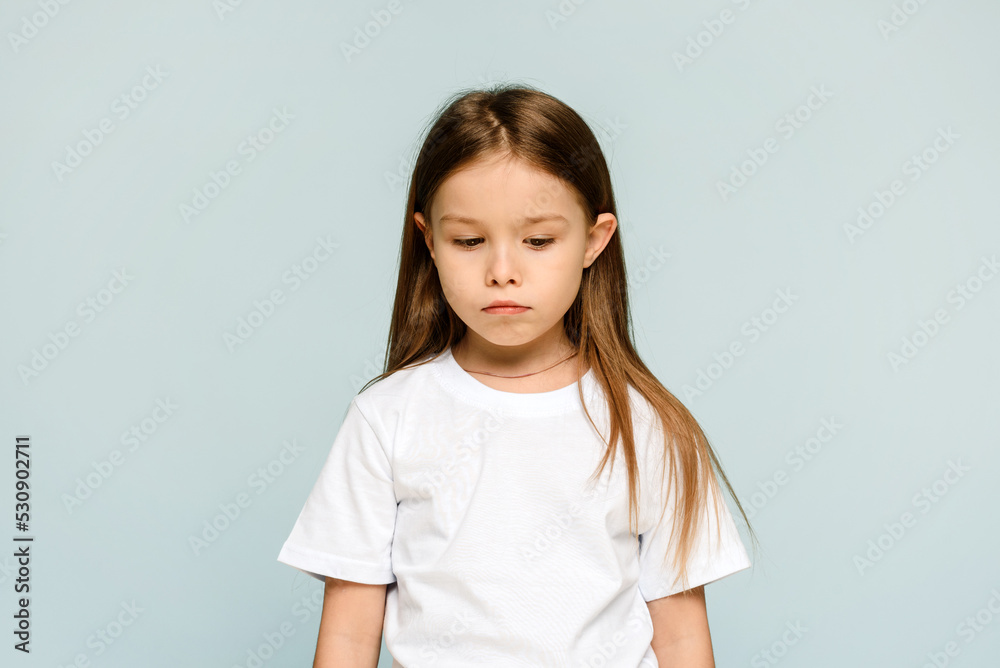 Dissatisfied little girl is offended on a blue background with copy space. Dissatisfied little girl is offended on a blue background with copy space.