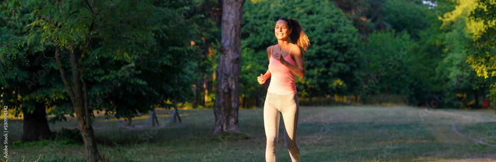 Young smiling fitness woman running in park in summer Young smiling fitness woman running in park in summer