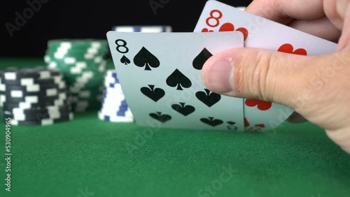 Poker game with a pair of eights betting all the poker chips. Close-up of a gambler hand is holding playing cards in poker club