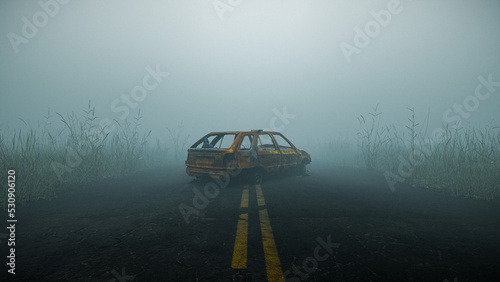 Destroyed abandoned car in the middle of a misty foggy road in the woods