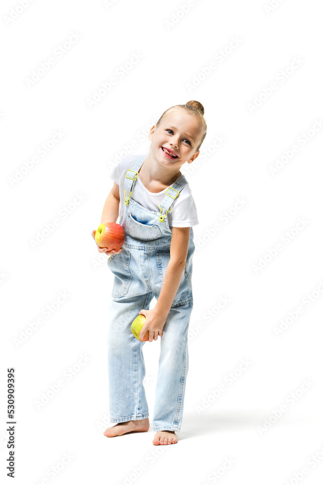 Cute girl dressed in denim overalls with apples on a white background. Cute girl dressed in denim overalls with apples on a white background.