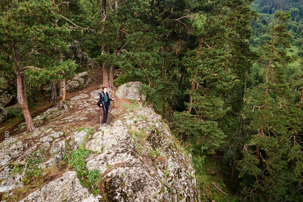 Hiker on top of mountain, woman take off backpack on the edge of the rock. Aerial wide footage