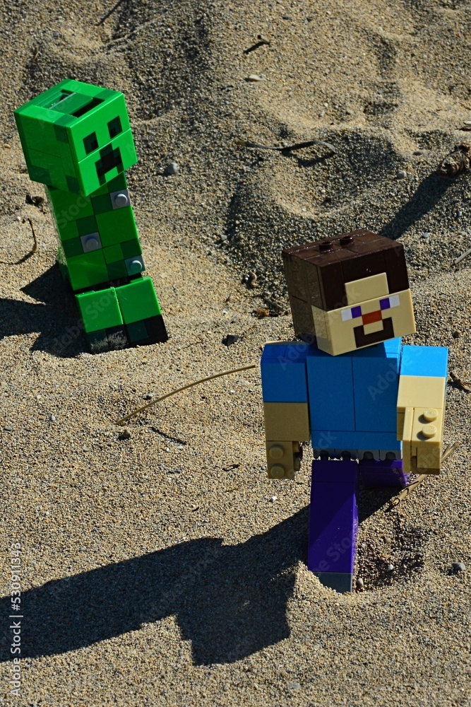 LEGO Minecraft large figure of main character Steve chased by green  explosive Creeper mob on sandy dunes, summer afternoon sunshine. Stock  Photo | Adobe Stock