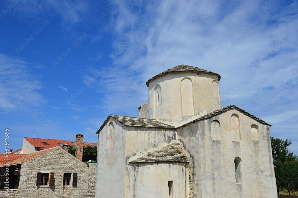 Back and right view of one of the oldest churches in Croatia, pre-romanesque Church of The Holy Cross in Nin. Summer partially cloudy day, scattered clouds. 