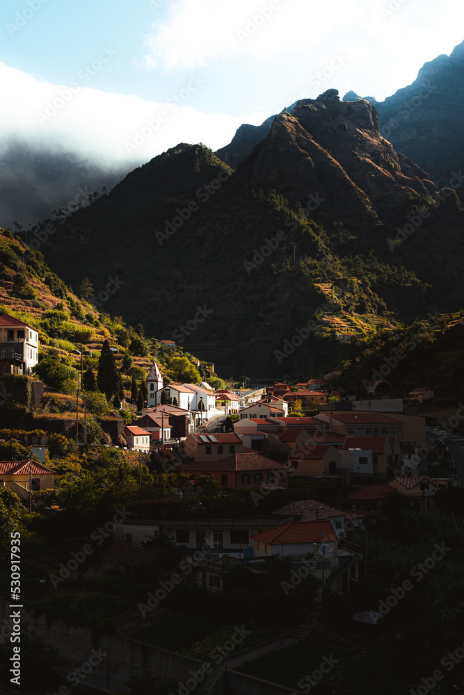 Half of village getting the sun light coming through the mountains of Madeira island.