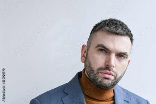 Portrait of handsome man wearing light blue blazer combined with fashionable beige sweater. 