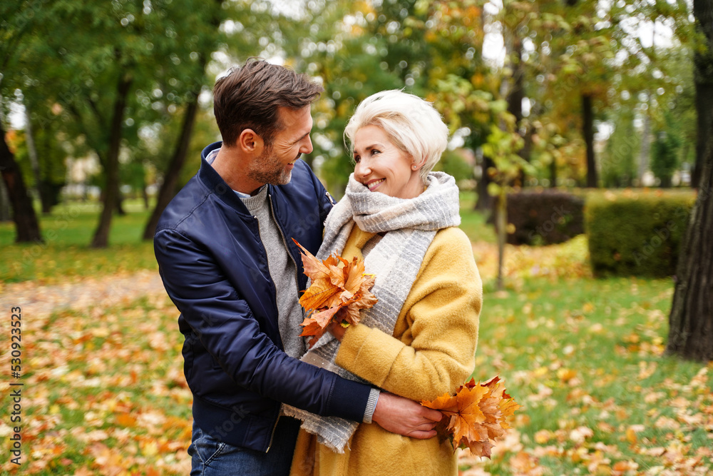 Fototapeta premium Happy Couple posing together Outdoor in the golden autumn park, looking at eachother and smiling. Wife and husband in love.