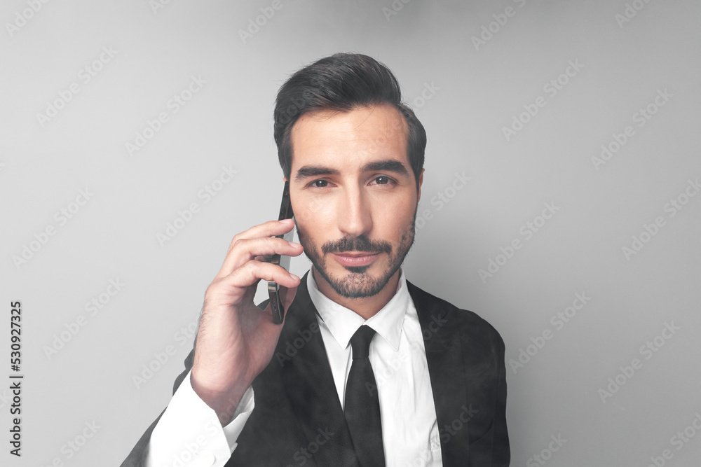 Man businessman in a suit talking on the phone solving important issues in wide angle on a gray background Man businessman in a suit talking on the phone solving important issues in wide angle on a gray background