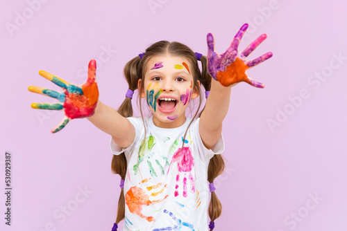 A little girl painted with multicolored paints will playfully have to create on a pink isolated background. Development of children s creativity for schoolchildren.