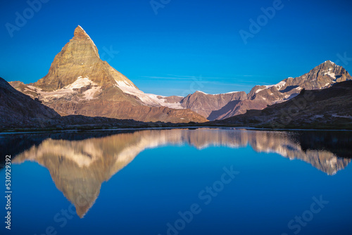 Matterhorn iconic mountain and lake relfection at peaceful sunrise, Swiss Alps © Aide
