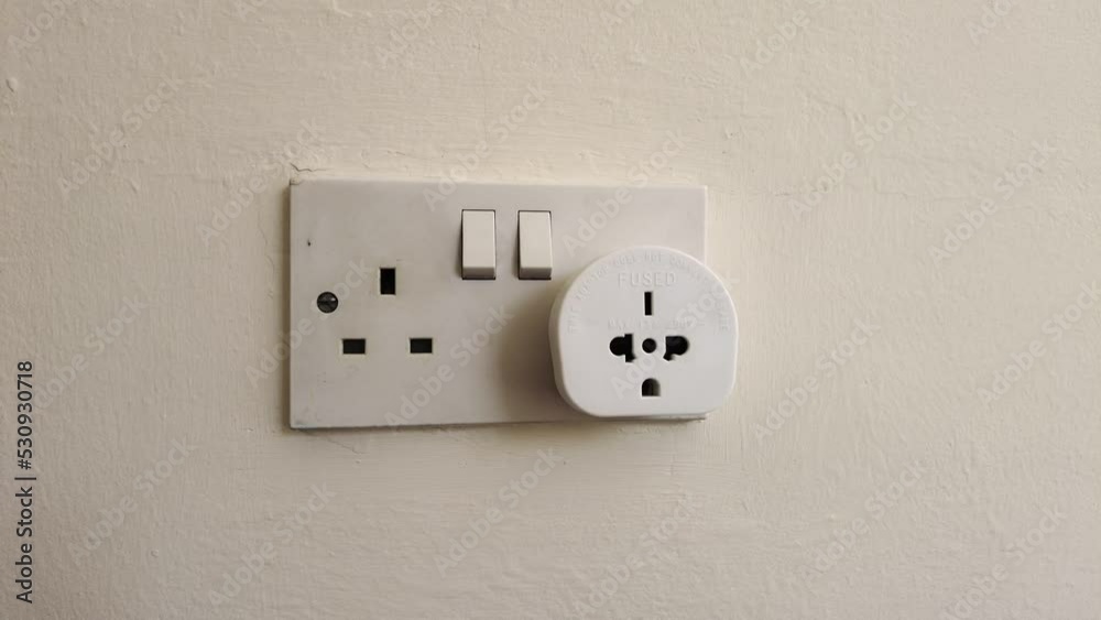 Plug in electrical appliance with adapter and switch on, UK British