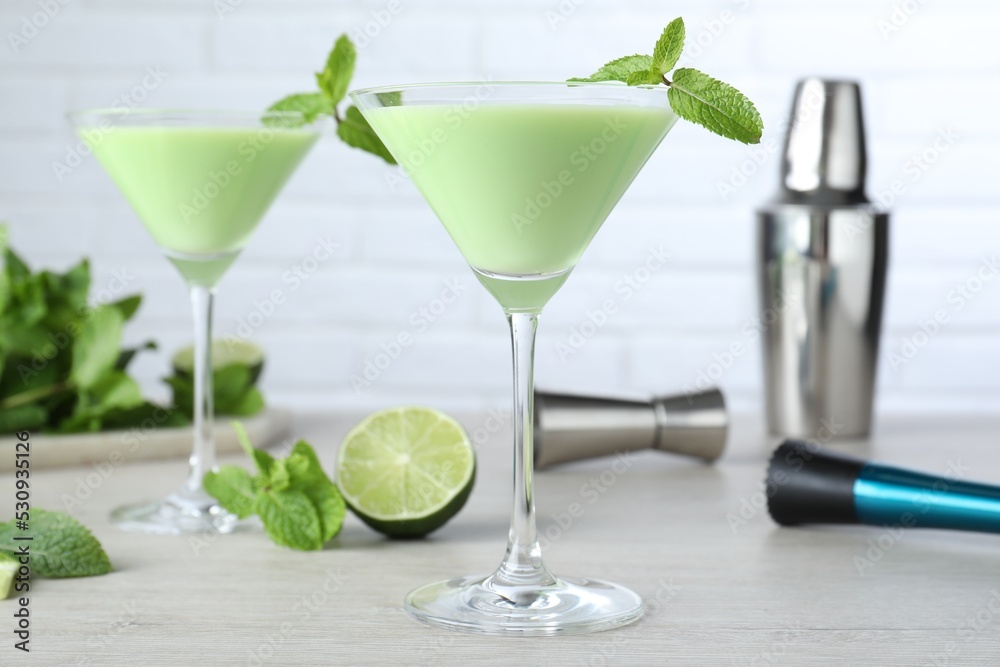 Delicious mint liqueur with green leaves on white wooden table Delicious mint liqueur with green leaves on white wooden table