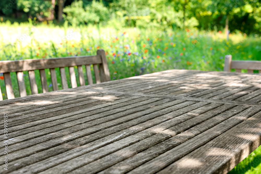 Empty wooden table with bench on sunny day in garden Empty wooden table with bench on sunny day in garden