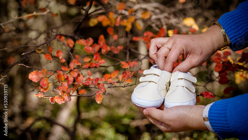 Manos de mujer con zapatos de bebé, en otoño photo