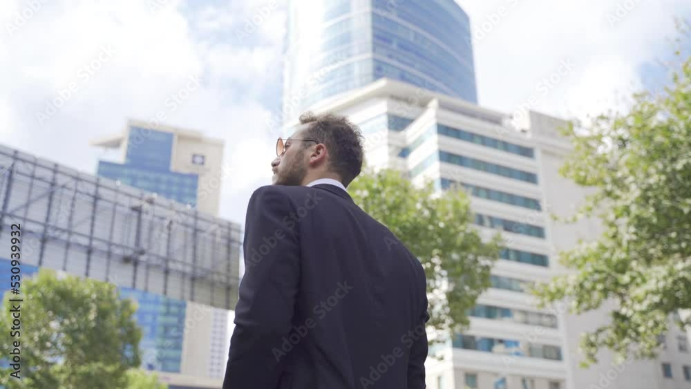 Businessman walking against high-rise business centers.
Businessman walks on the modern streets of the city center.
Businessman walking against high-rise business centers.
Businessman walks on the modern streets of the city center.