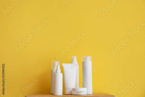 Bath accessories on wooden shelf near yellow wall