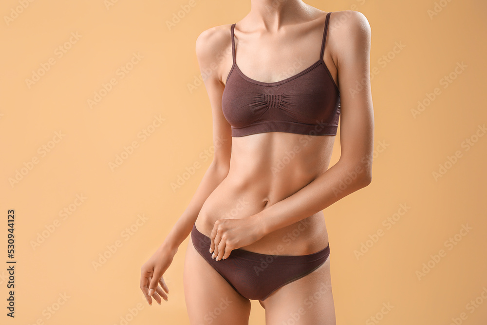 Obraz premium Slim young woman in underwear on beige background