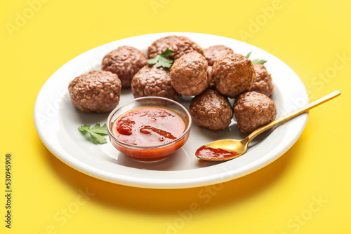 Plate with tasty meat balls, parsley, sauce and spoon on yellow background © Pixel-Shot