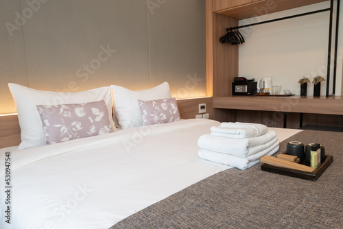 Side view of hotel amenities (such as towels, shampoo, soap, toothbrush etc) on the bed.