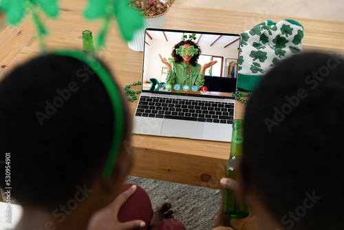 African american couple having st patrick's day video call with friend on laptop at home
