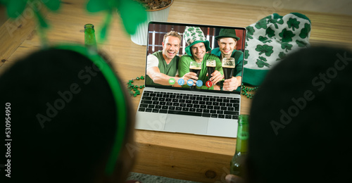 African american couple having st patrick's day video call with male friends on laptop at home