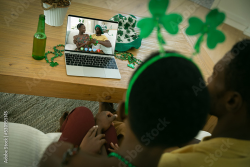 African american couple making st patrick's day video call with smiling couple on laptop at home